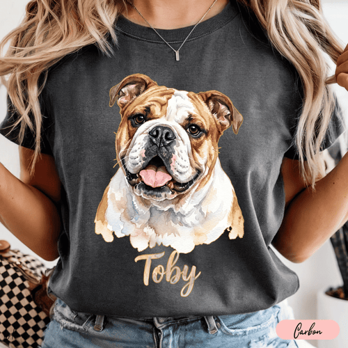 Playera color carbón con retrato en acuarela de un bulldog y nombre Toby en tipografía cursiva.