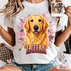 Mujer usando playera blanca personalizada con retrato de golden retriever, salpicaduras rosas y nombre Lola en letras grandes.